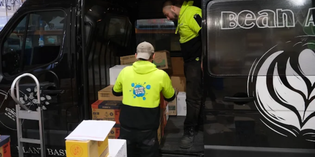 A man loading boxes labeled 'Coffee Beans' into a van, preparing for delivery as a coffee bean supplier.