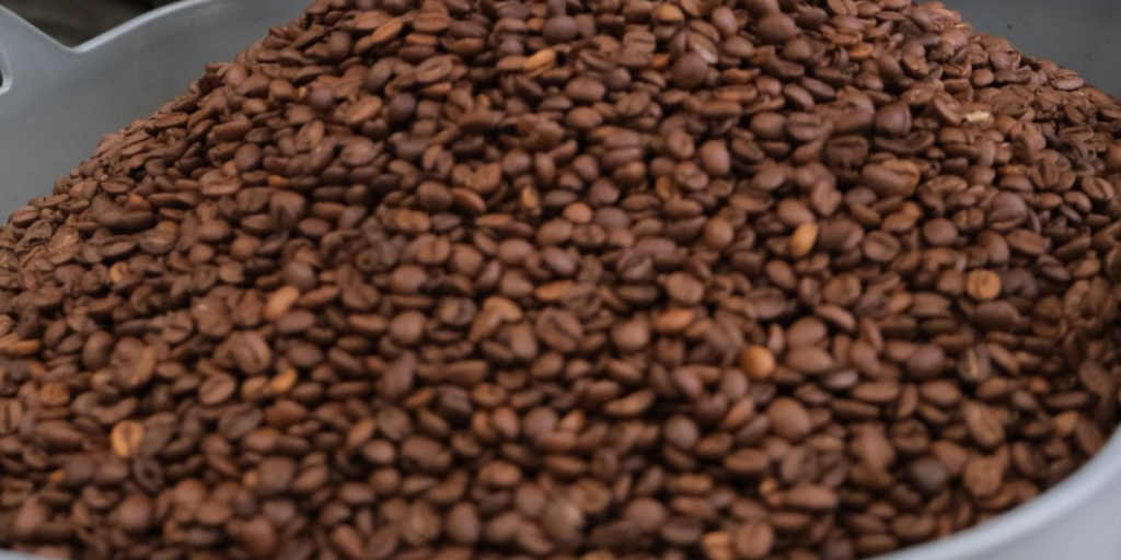 A metal container filled with a large pile of coffee beans, representing offerings from a coffee bean supplier.