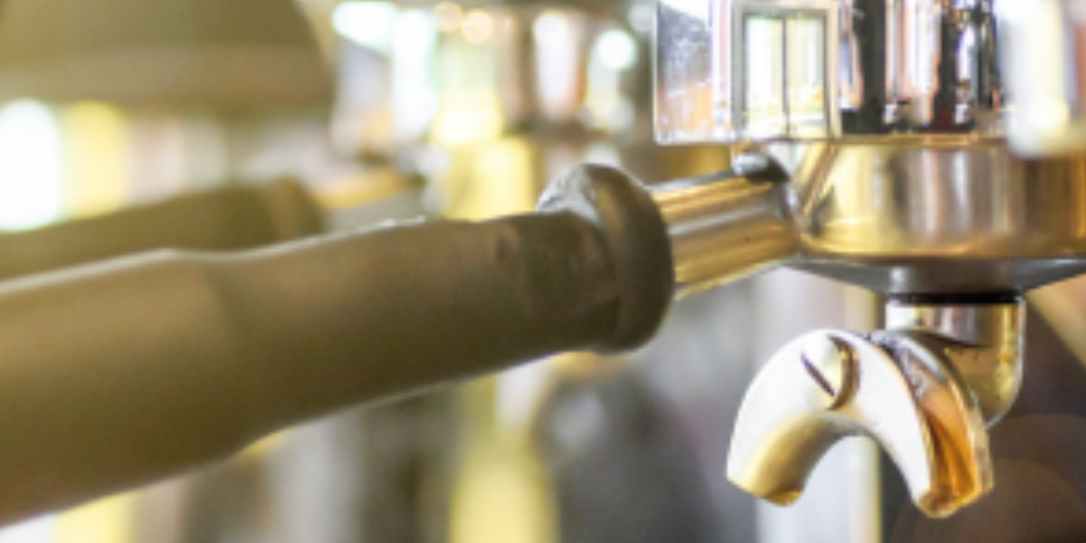 Close-up of a coffee machine featuring a metal handle, highlighting its design and potential for bacterial growth if uncleaned.