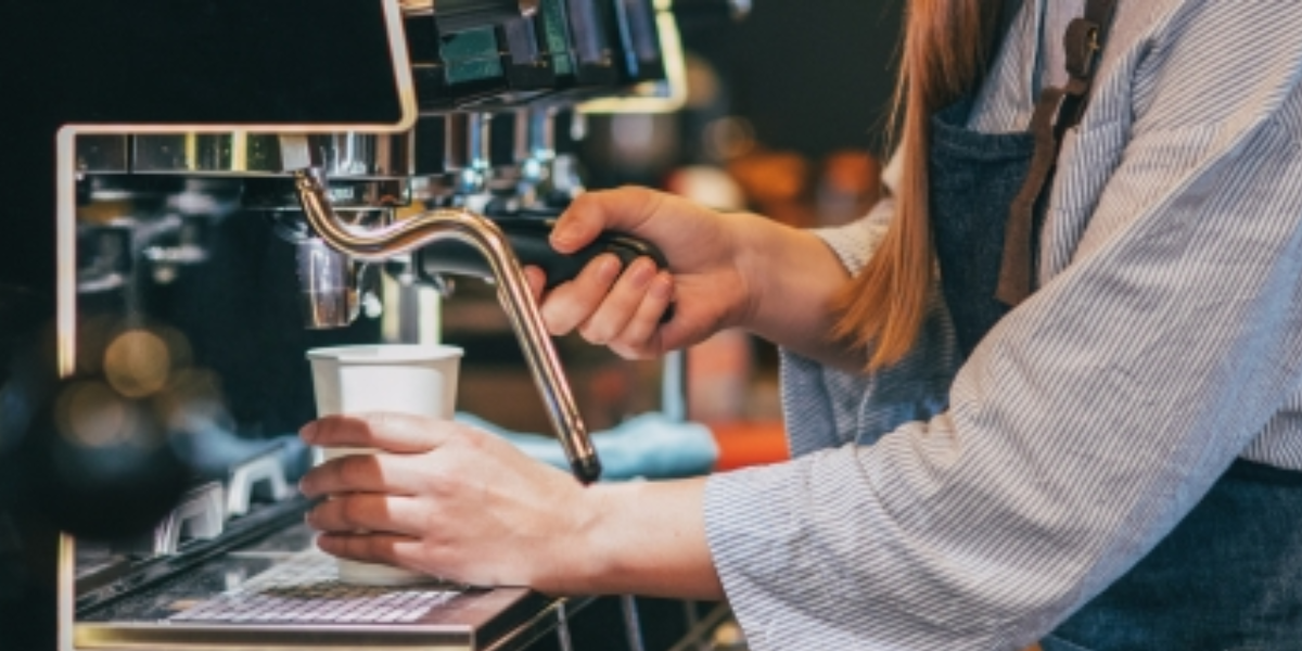 A woman brews coffee in a busy coffee shop, highlighting the importance of machine maintenance for optimal service.