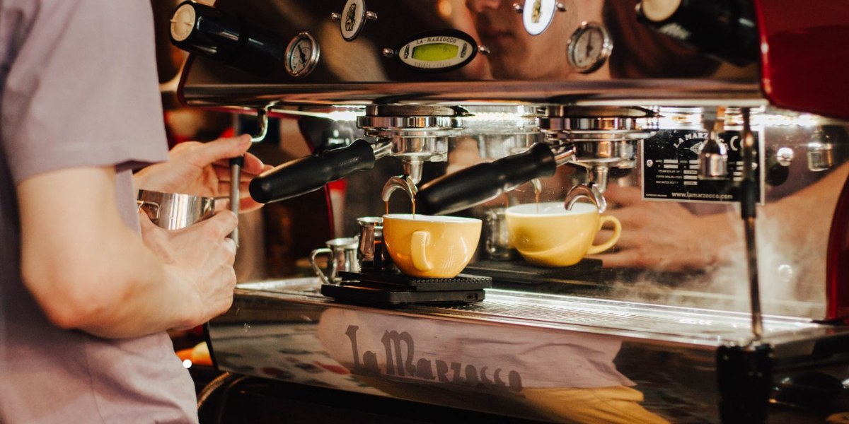 A person stands in front of a coffee machine, ready to prepare coffee, highlighting Bean Around Town's services for businesses.